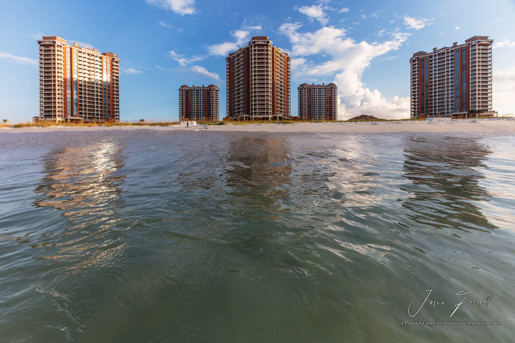 An early morning sunrise photo of the Portofino Island Resort Towers from the Gulf of Mexico.