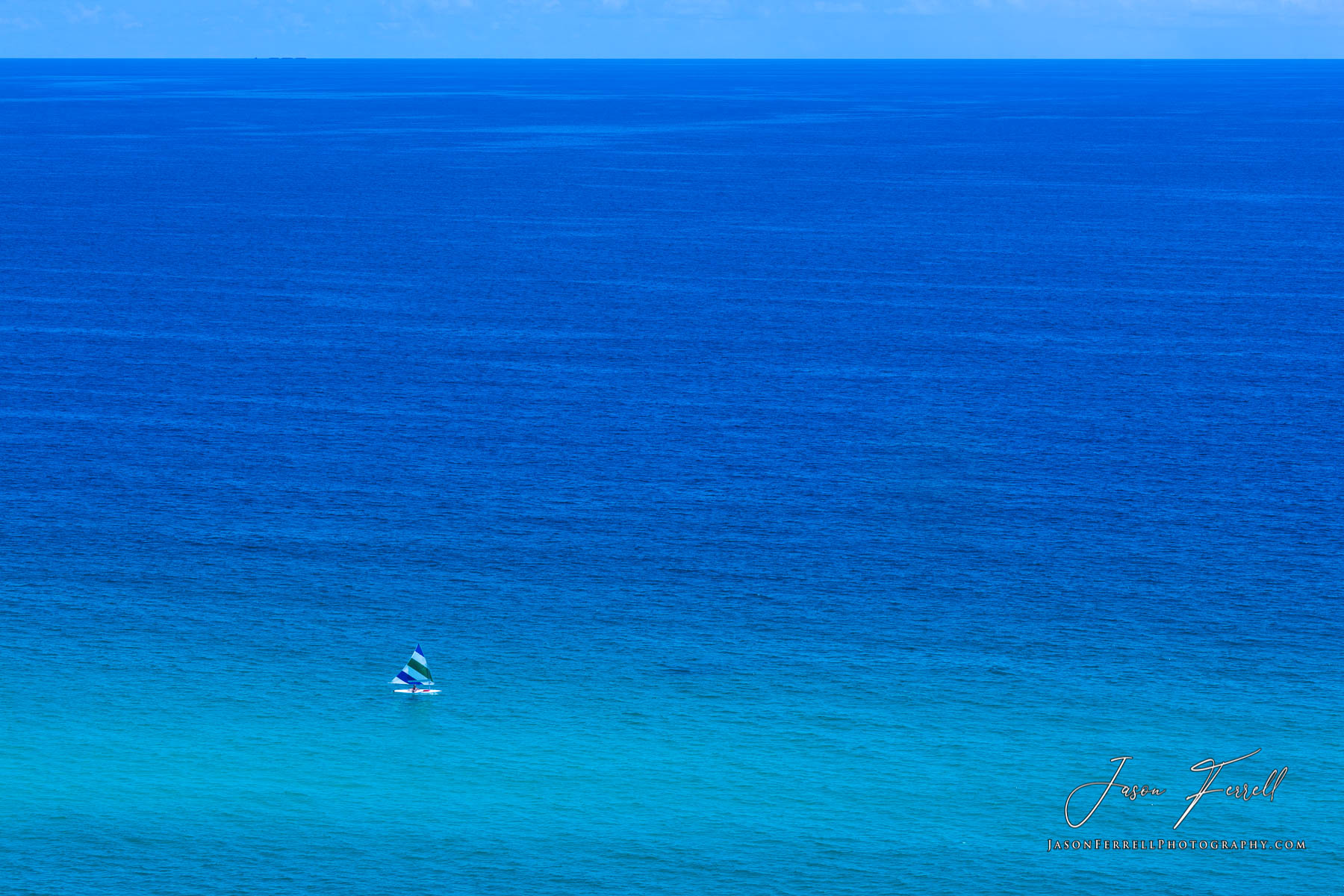 The vast open waters of the Gulf of Mexico with a single person on a sailboat.