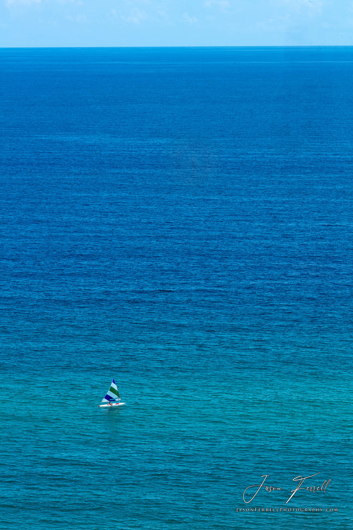 The vast open waters of the Gulf of Mexico with a single person on a sailboat.
