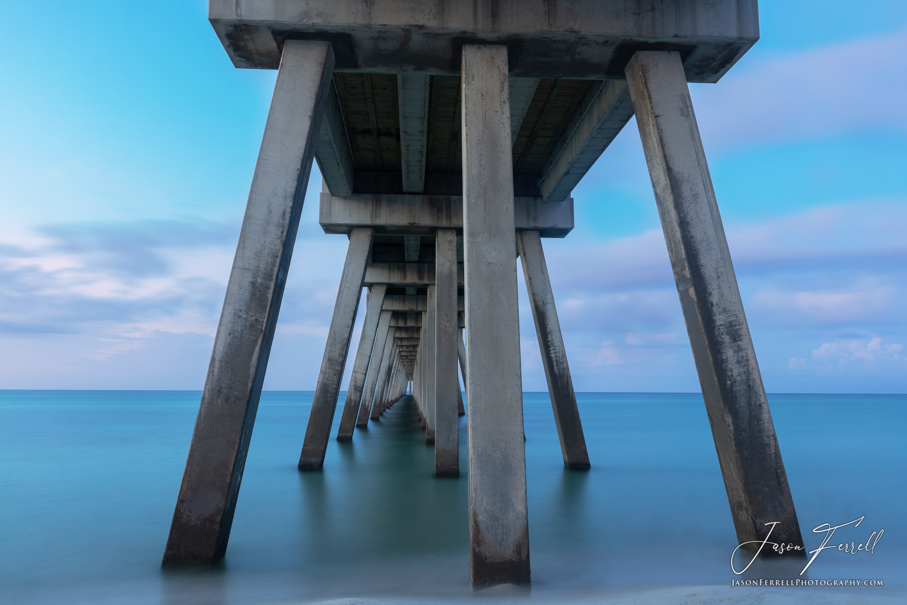 The pillars underneath this pier create a long narrow passageway into the ocean.  As the sunrise came about, the sky lit up beautifully...